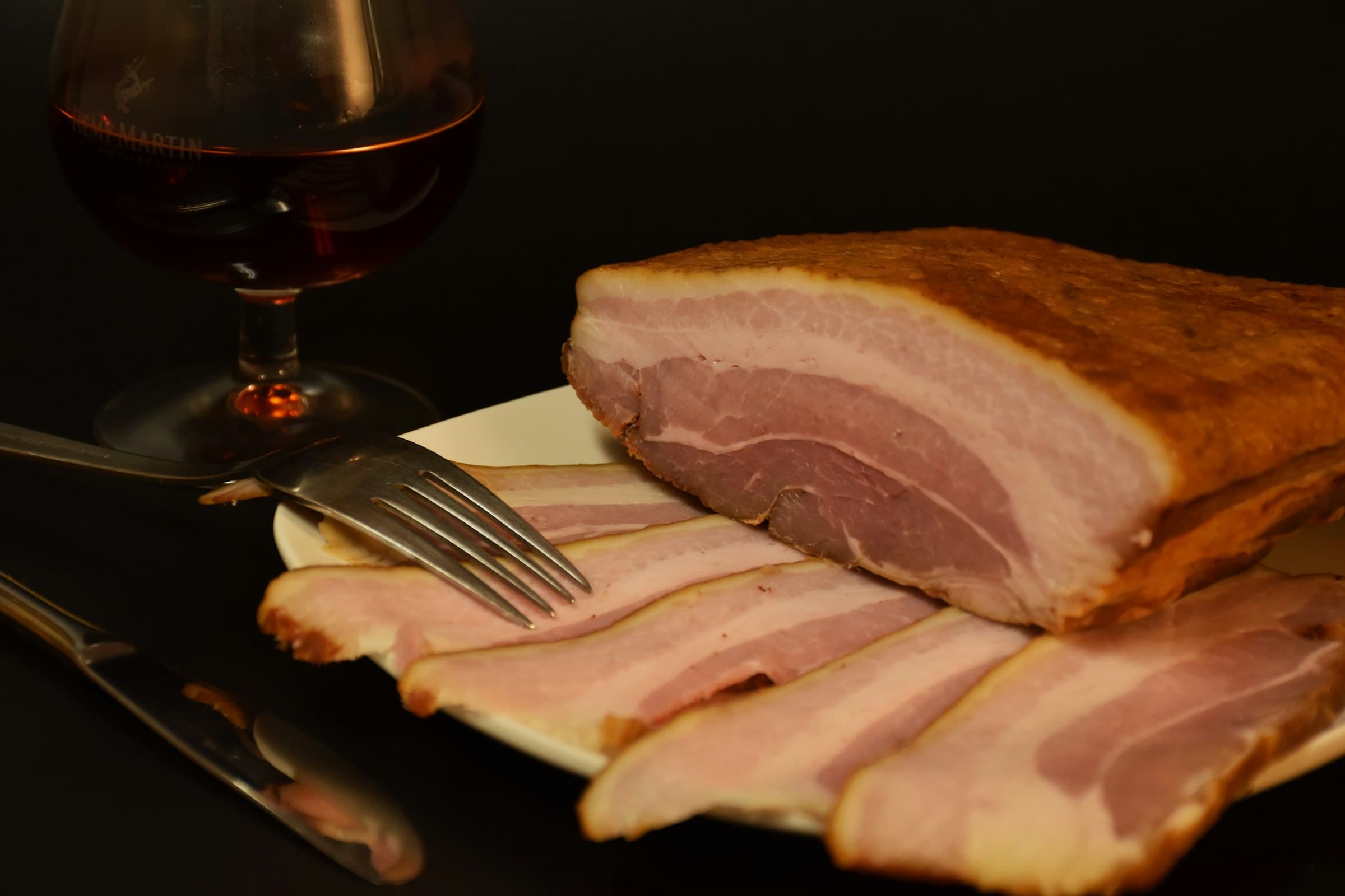 A slab of home-cured bacon with slices cut from it — how to dry cure bacon at home