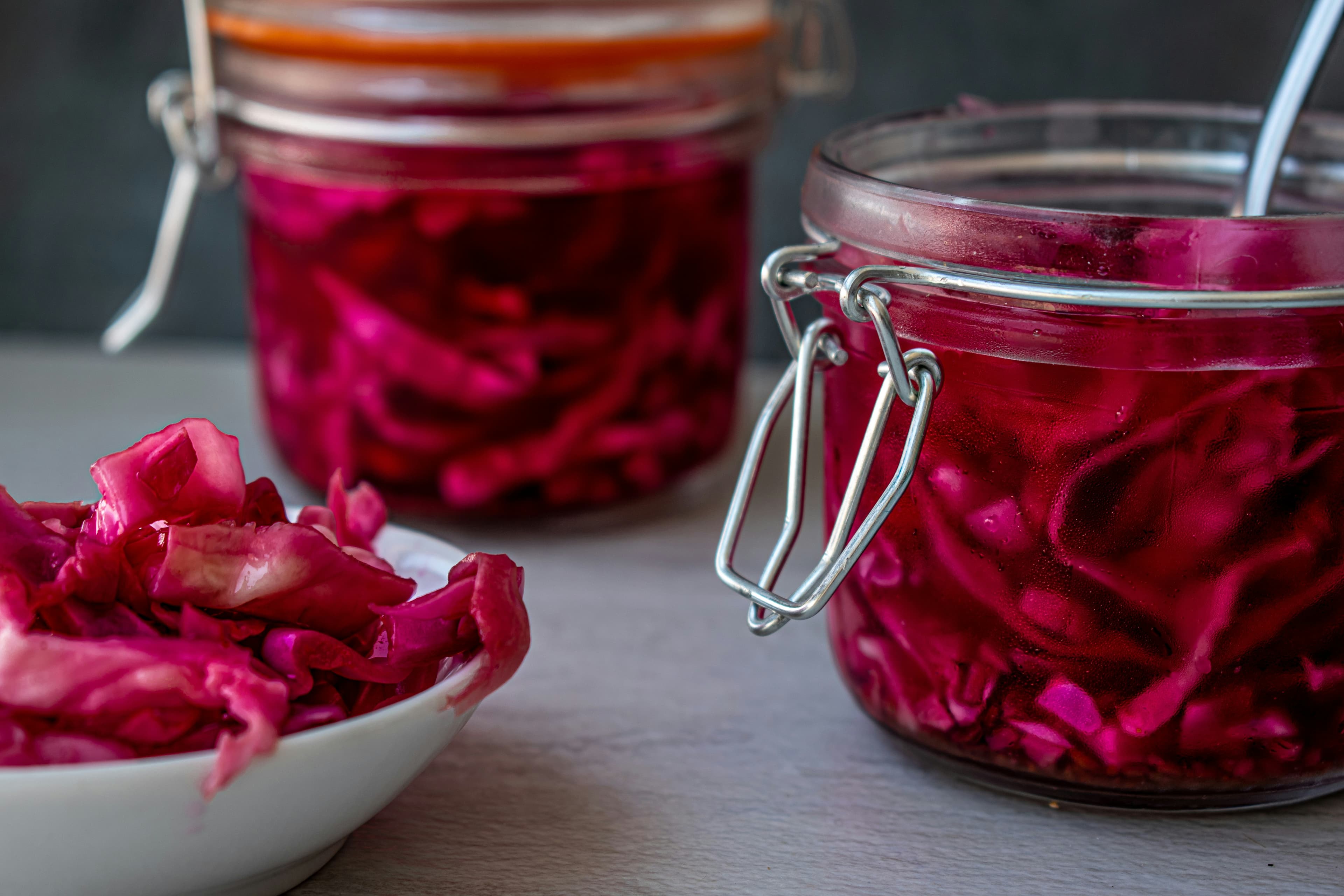 Vibrant pink fermented red cabbage in glass jars — health benefits of probiotic fermented foods